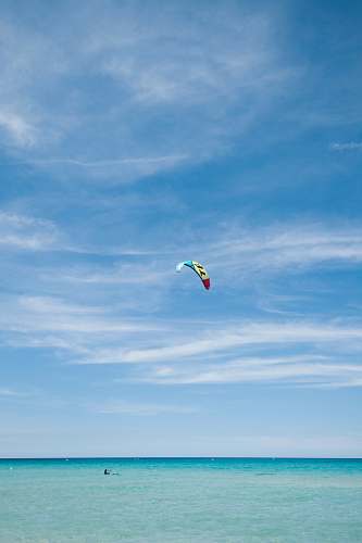leisure activities person paragliding under blue and white skies during daytime gliding
